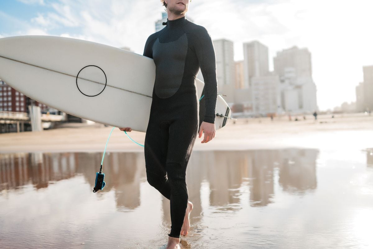 Man in a wetsuit holding a surf board.