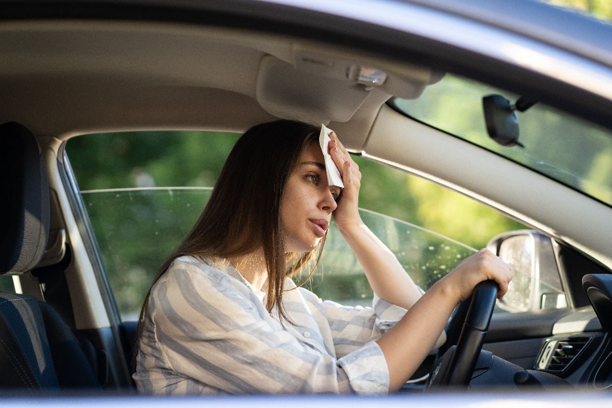 Woman in car feeling hot.