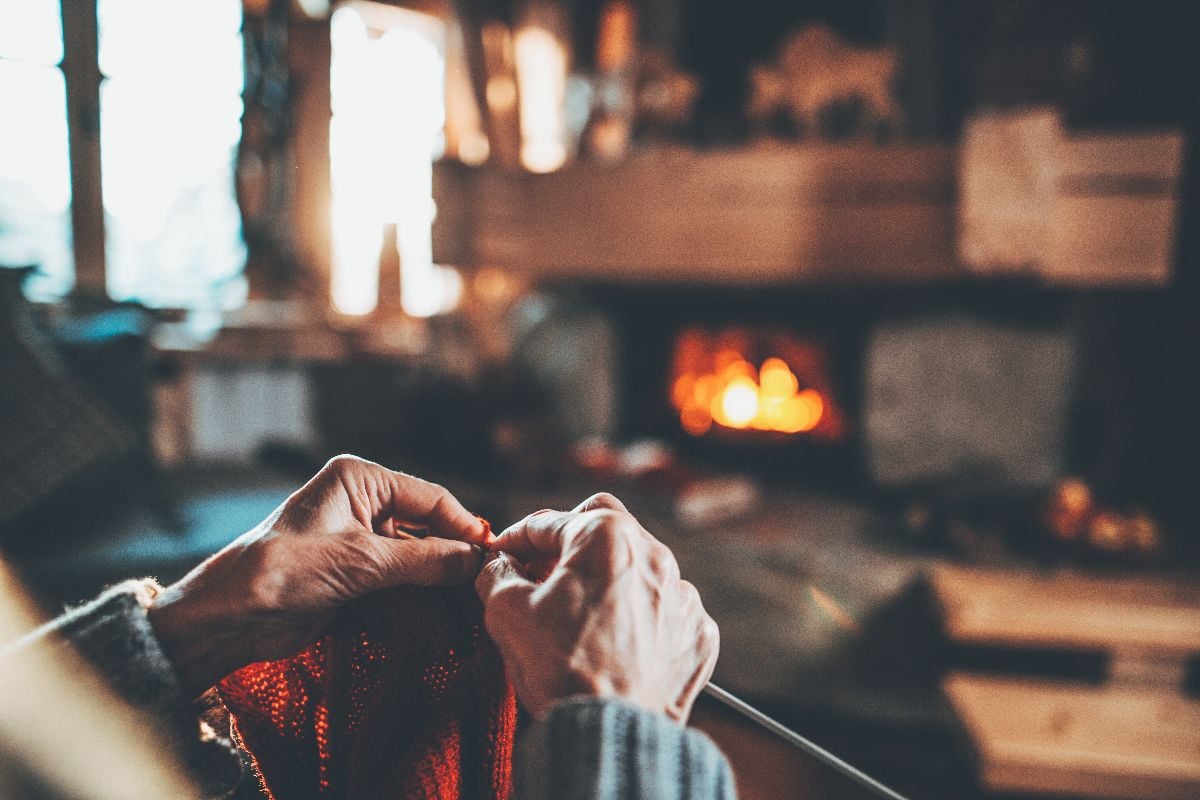 Grandmother knitting by the fireplace.