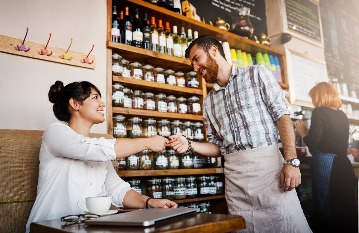 Customer giving money in cafe.