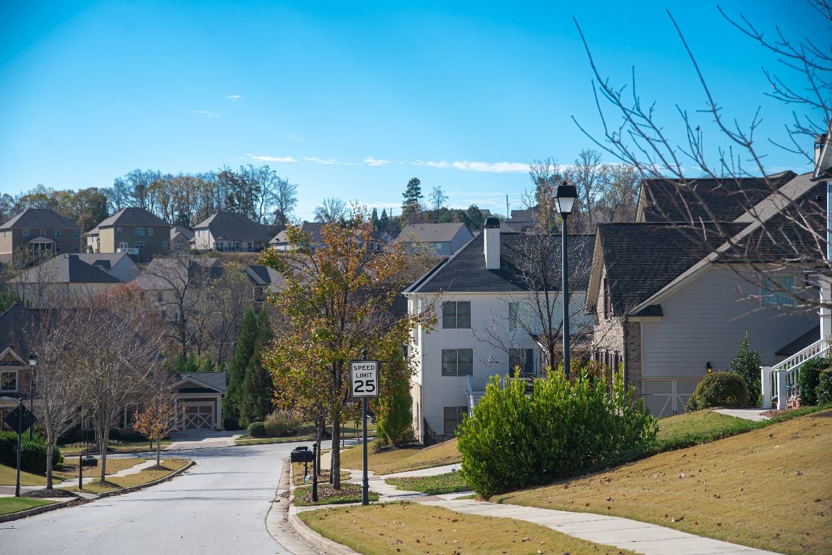 Row of two-story houses along residential street leading down a steep hill in new development suburban neighborhood.