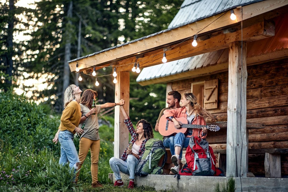 A group of friends having a good time at the back porch with guitar and drink.