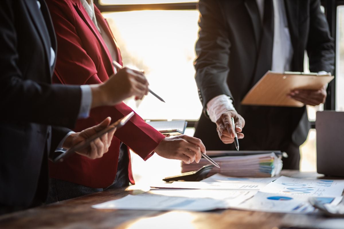 Group of people working with paperwork on a board room table.