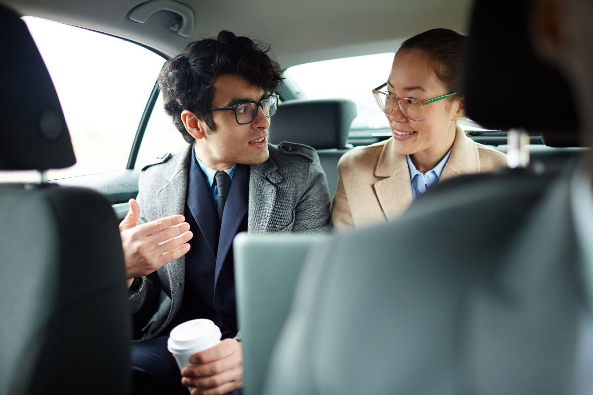 Modern traders having talk on backseat of car.