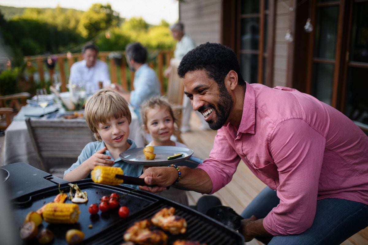 Multi generation family having bbq party outside the backyard patio.