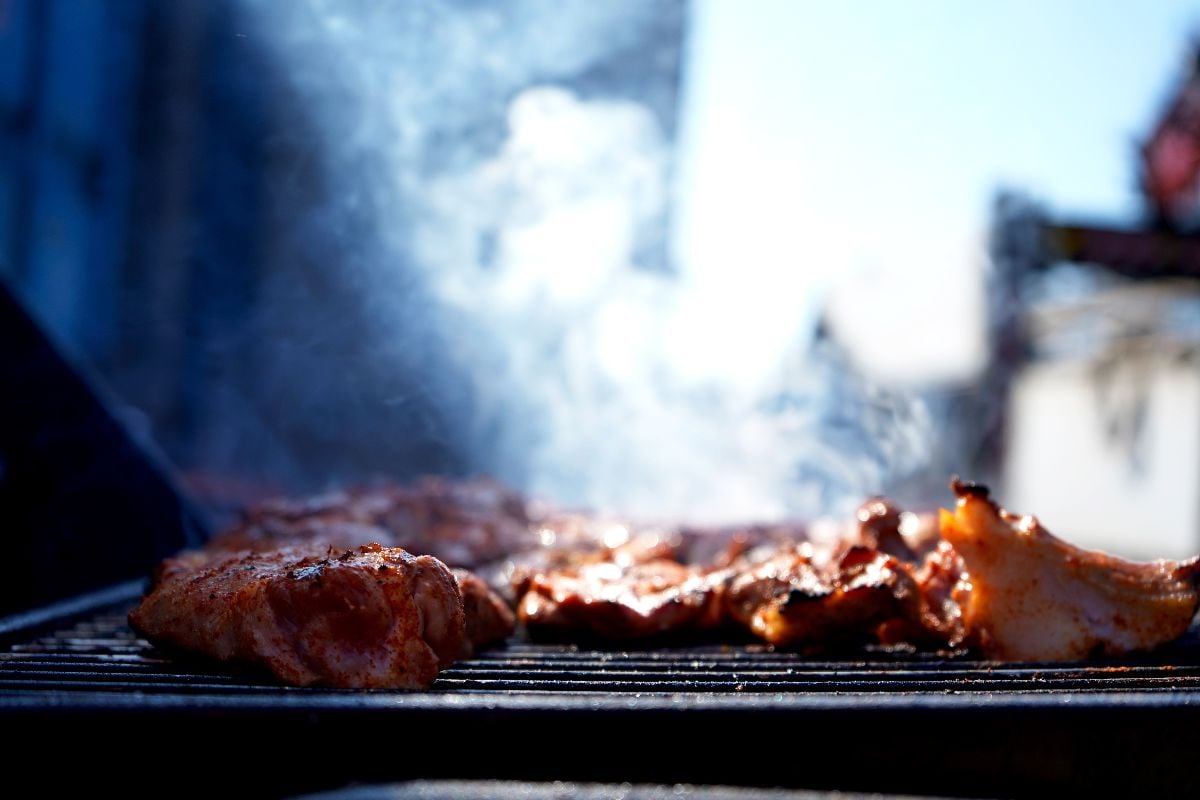 Juicy meat sizzles on the grill as smoky tendrils rise.