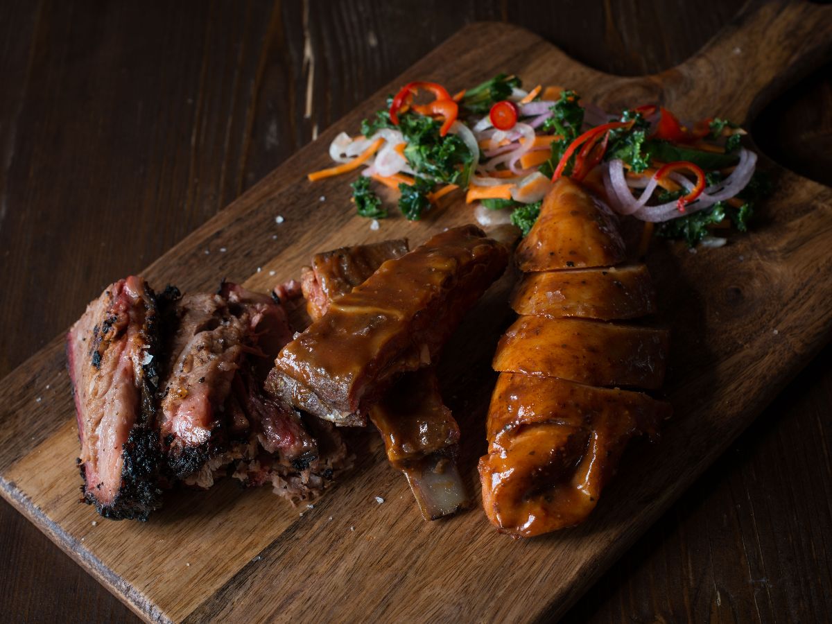 A mouthwatering barbecue platter featuring smoked brisket, glazed ribs, and juicy sausage, served with a side of fresh pickled vegetables.