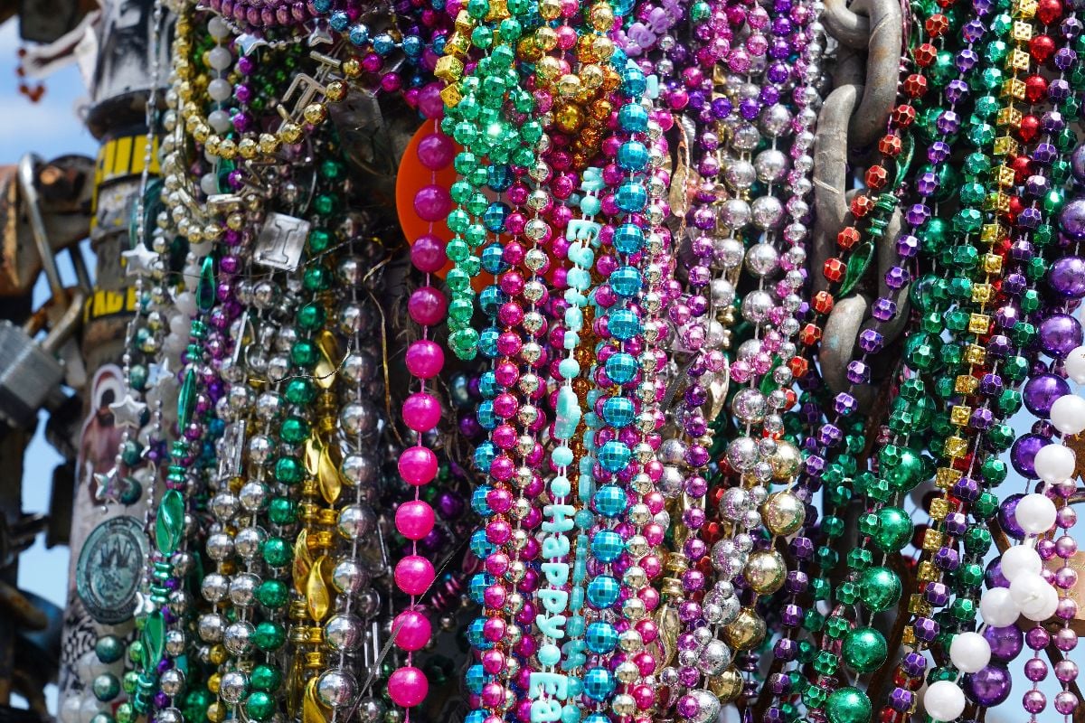 A collection of colorful Mardi Gras beads hanging on a fence in New Orleans.