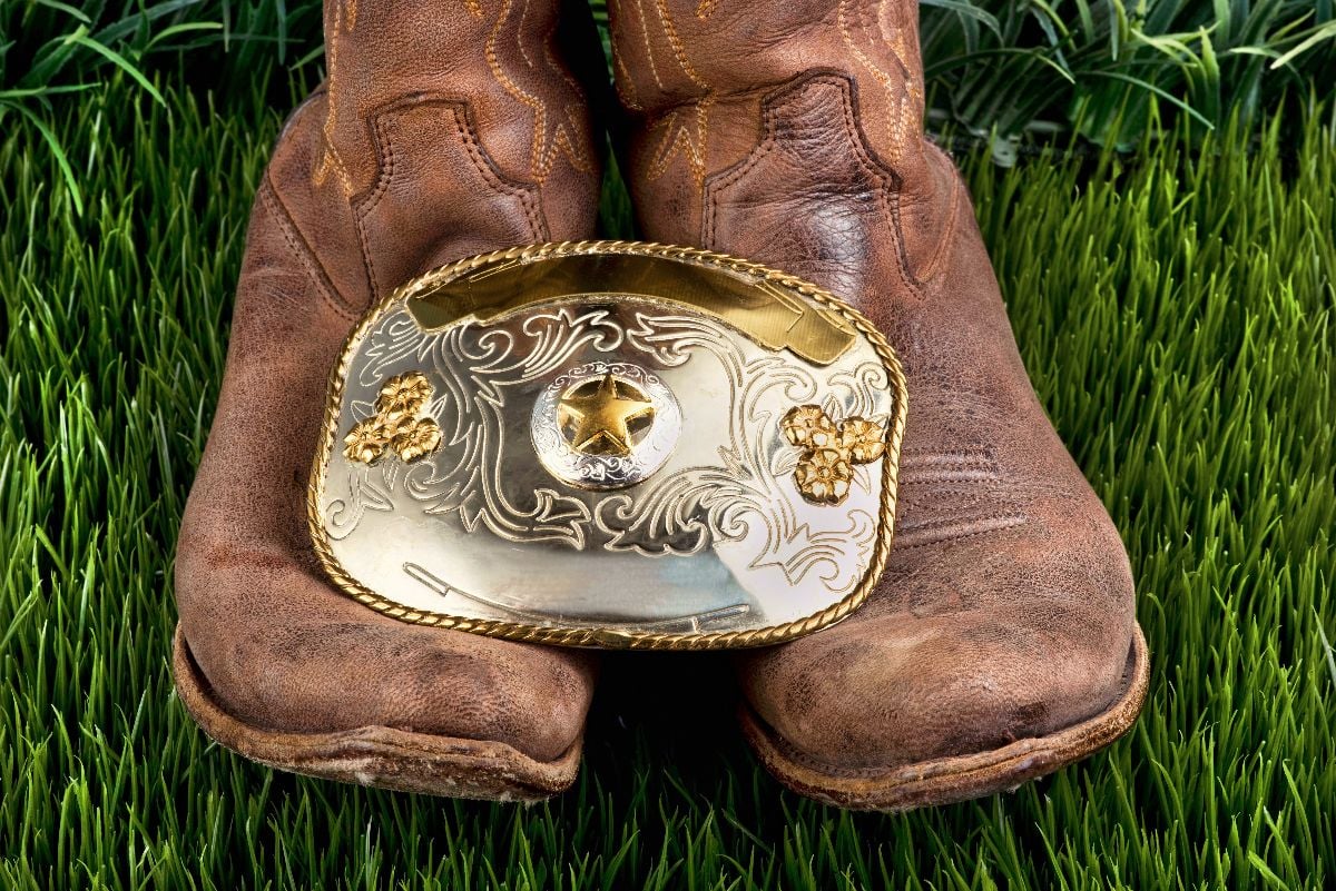 Cowboy boots and big silver cowboy belt buckle.