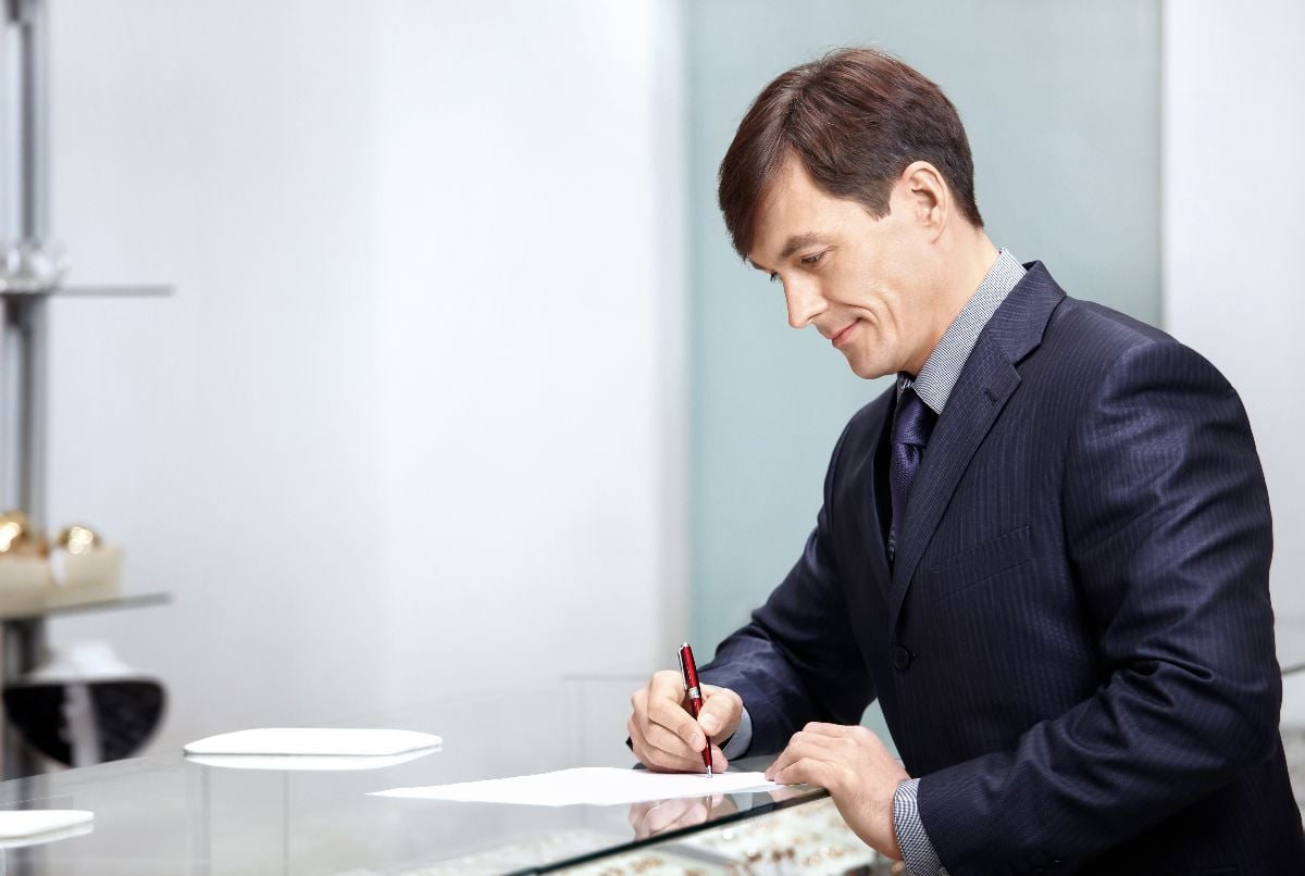 The businessman in a suit signs the important documents.