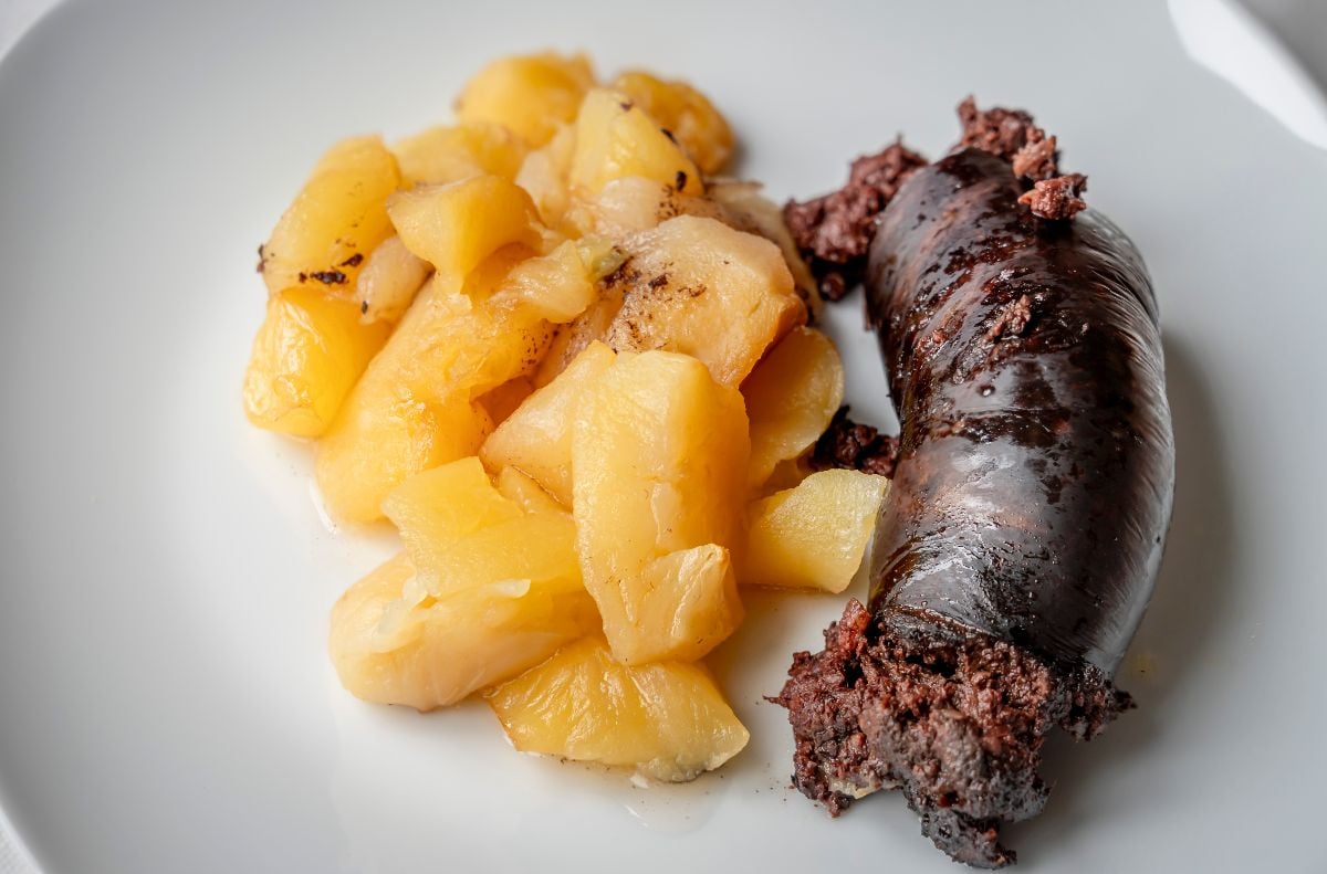 A plate with a piece of black pudding cut and apple compote.