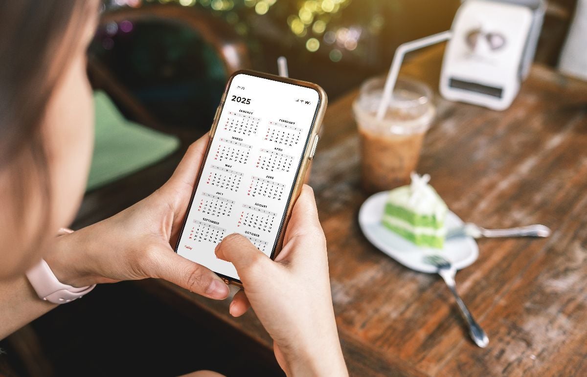 Businesswoman using smartphone with monthly calendar inside the cafe.