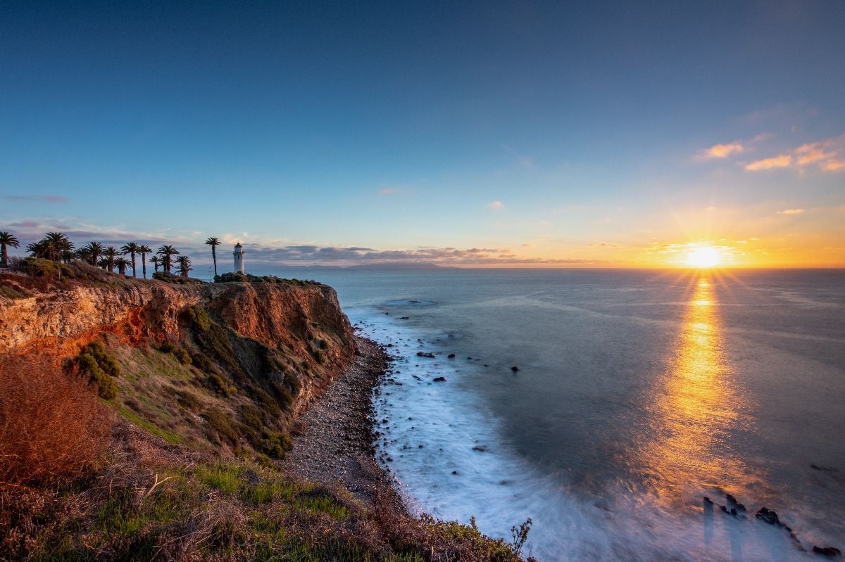 Sunset paints the sky above Point Vicente, casting golden hues over the rugged coastline.