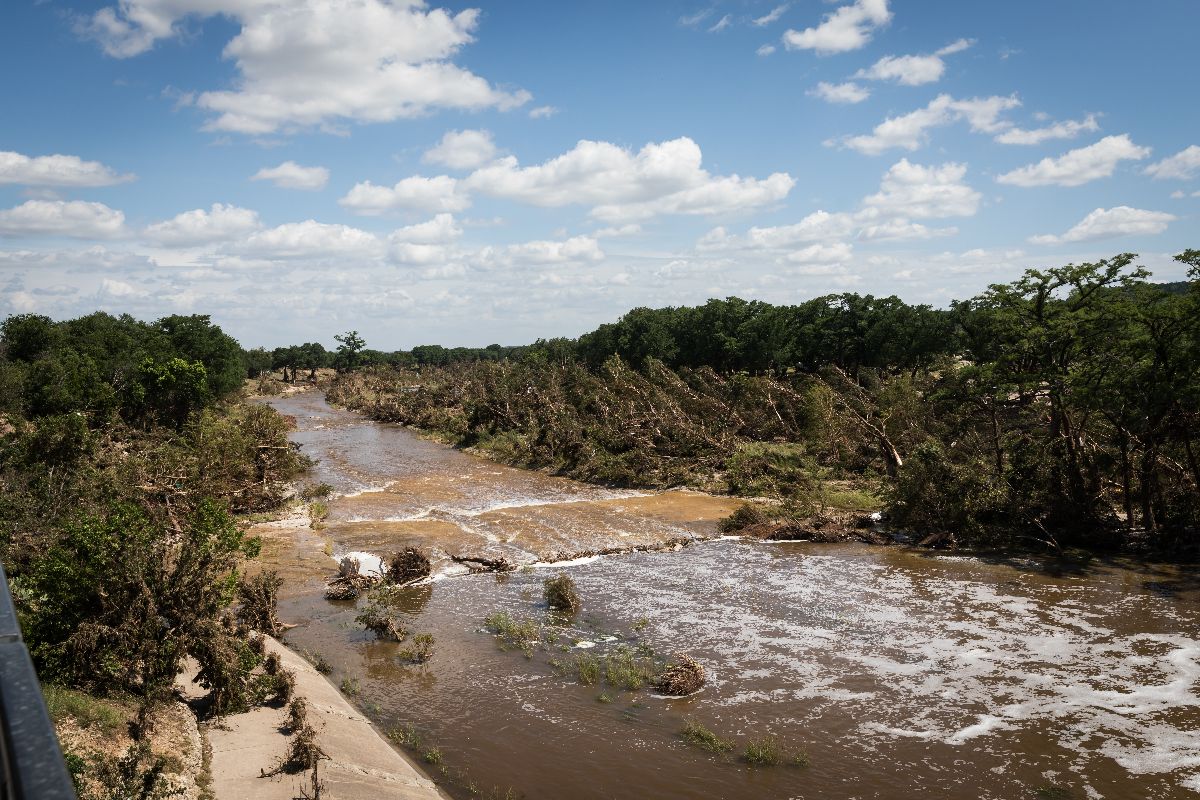 Rushing water and broken trees along the Guadalupe River in downtown Kerrville, Texas after the flood disaster.