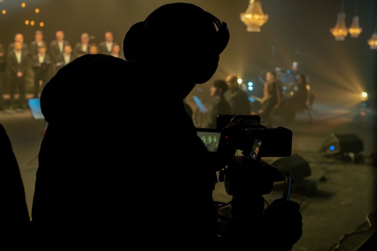 Cinematographer filming a stage performance in a studio with dramatic lighting.