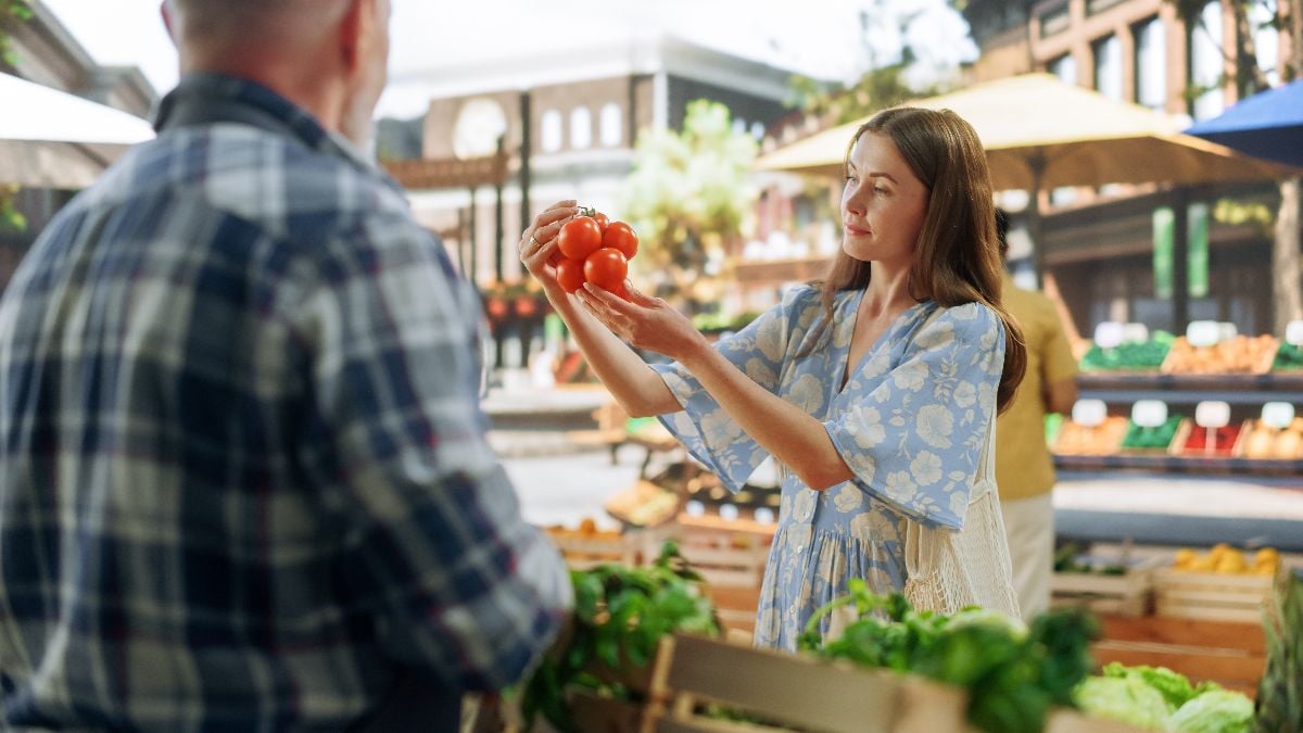Woman in a dress buying tomatoes.