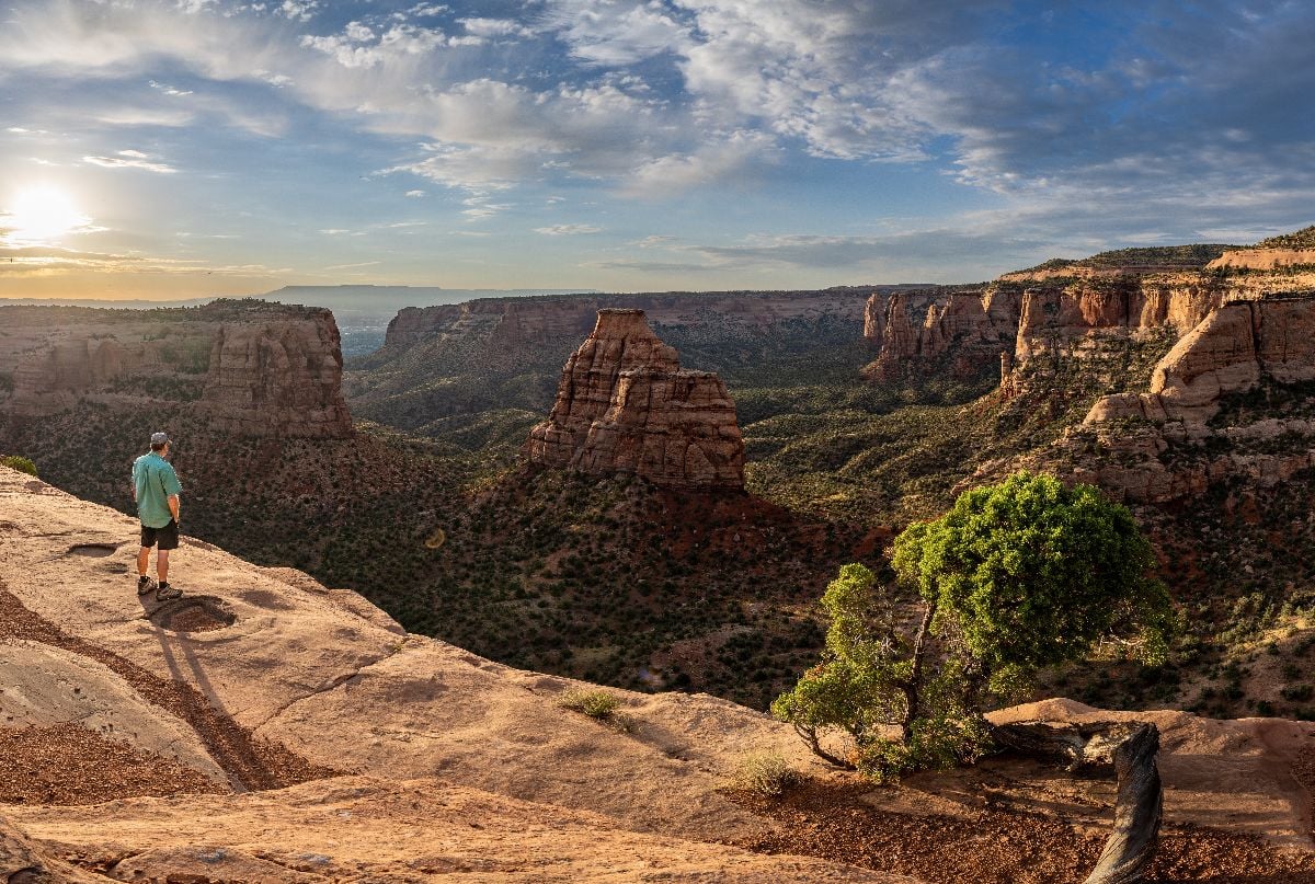Hiker watching a natural occurring free standing pillar at sunset.