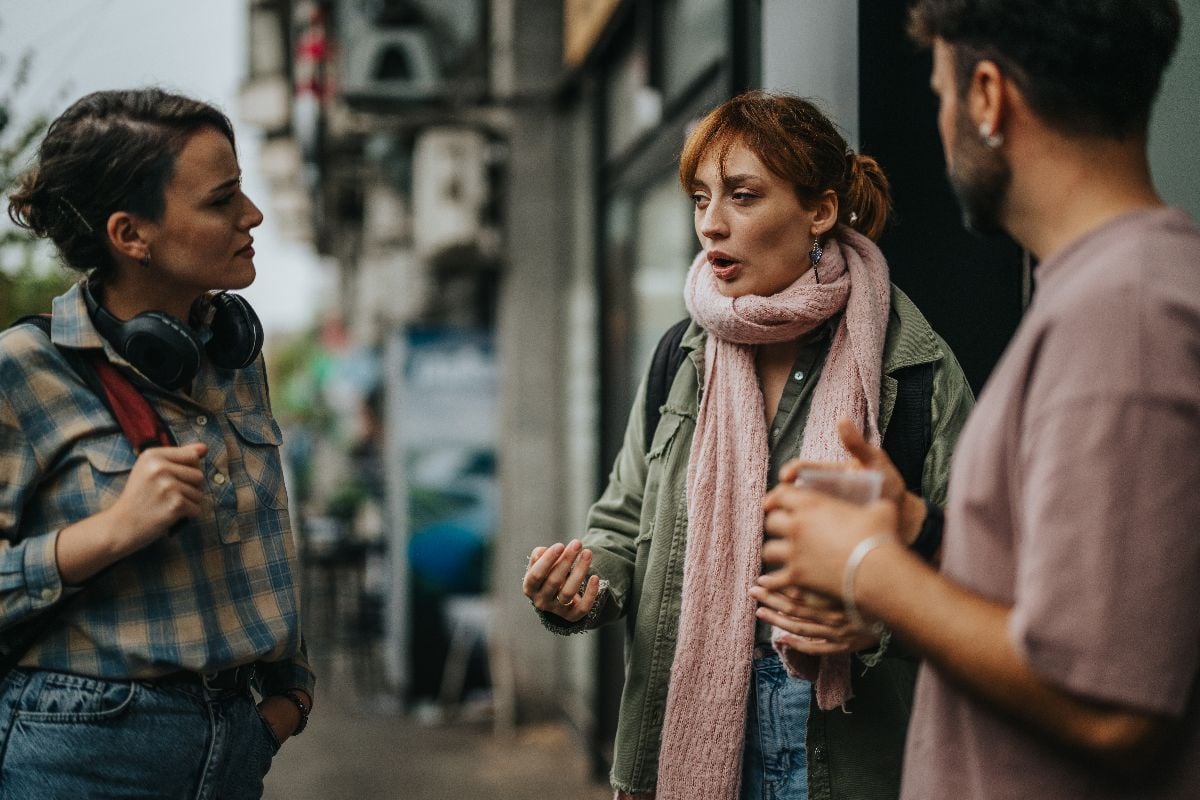 Three adults having conversation on a city street.