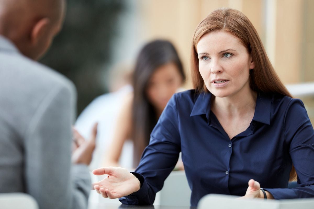 Businesswoman gesturing and talking to businessman.