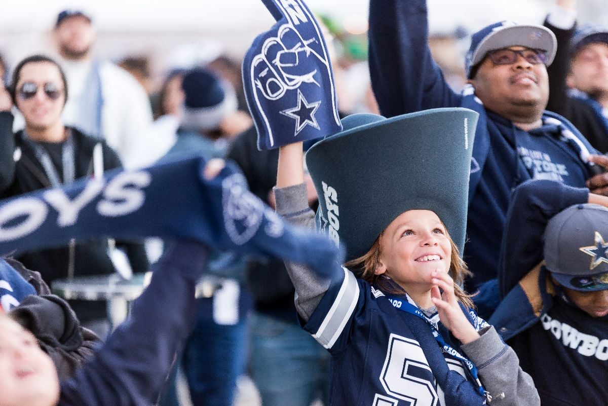 Young Dallas Cowboys fan in a big Cowboys hat outside AT&T Stadium.