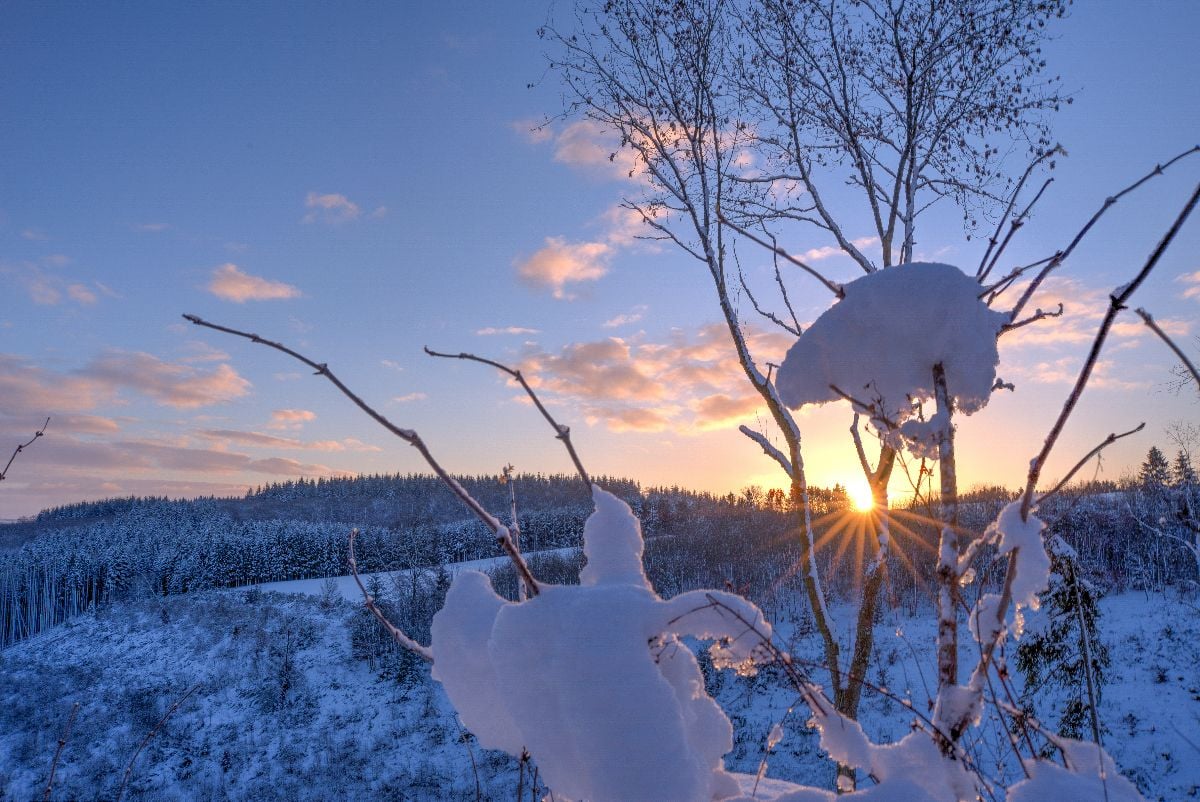 Sun peeking through the snowy mountains.