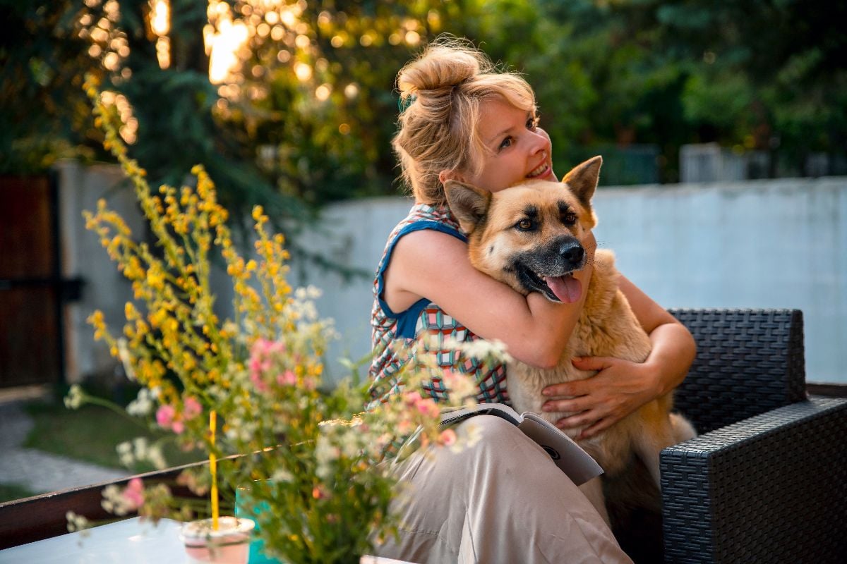 Woman on a porch hugging a dog.
