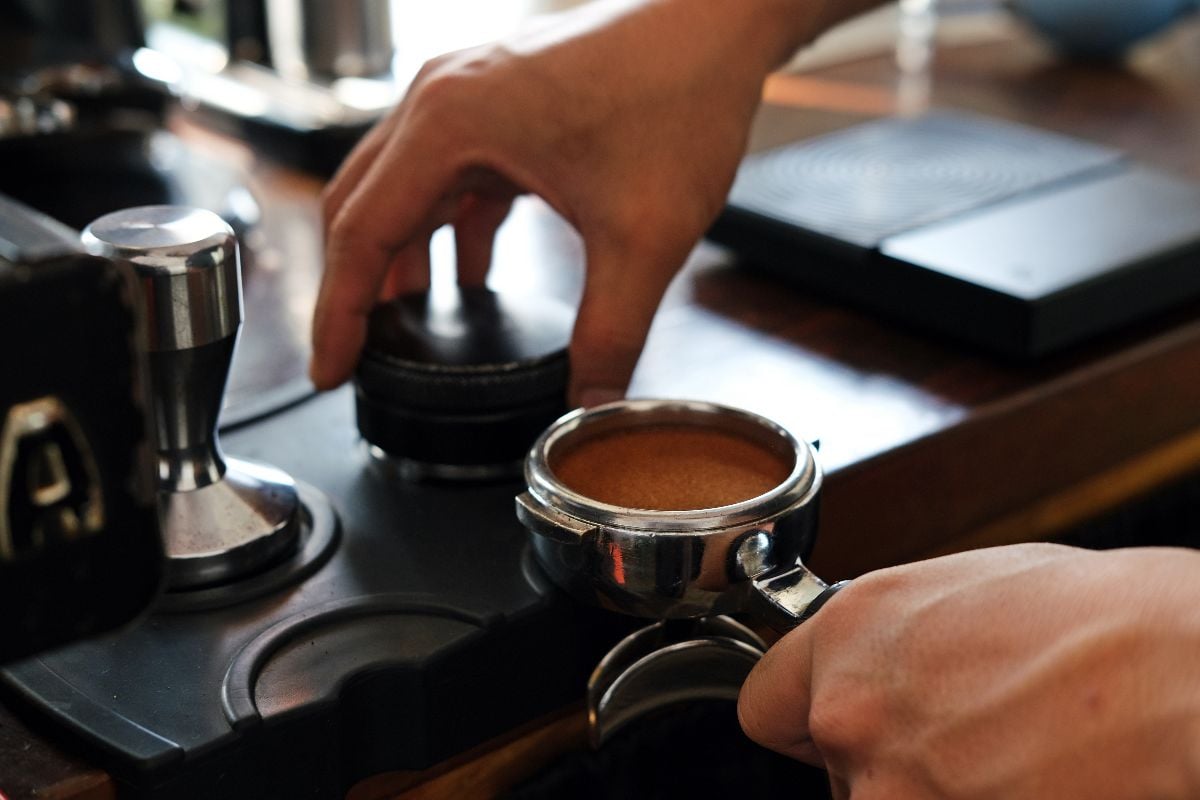 Close-up barista hands pressing espresso grounds.