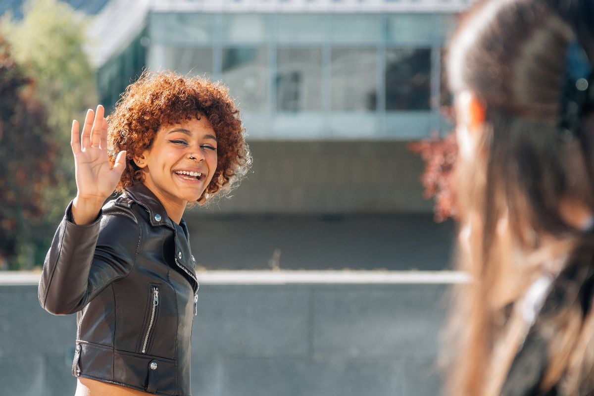 Women greeting each other on the street outdoors.