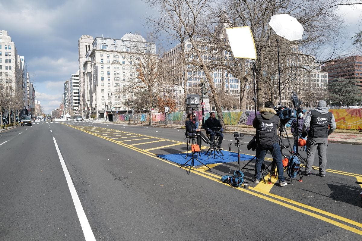A foreign news team reports live on the street.