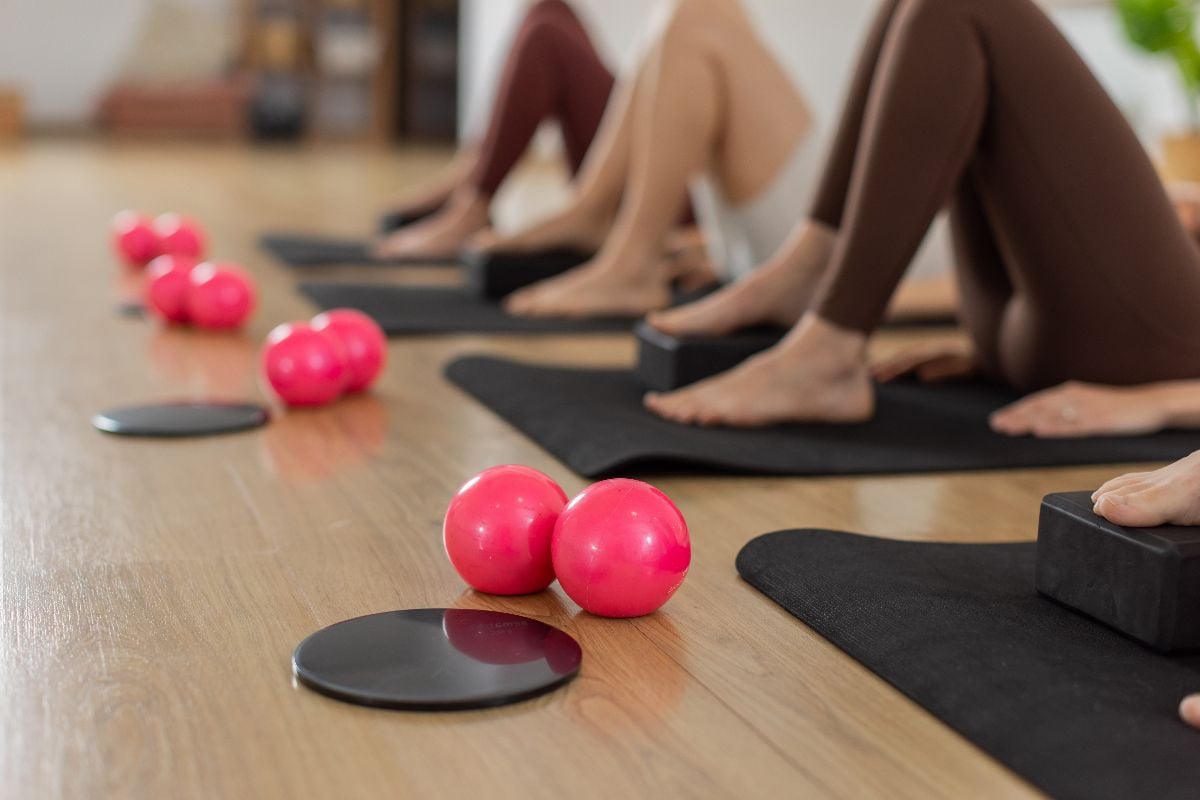 Pink mini balls, gliding discs and bare feet on black mats.
