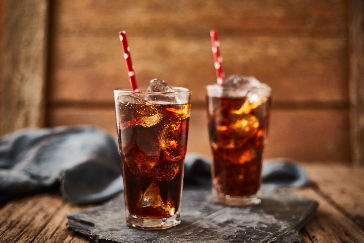 Close up glass of cola with ice on table.