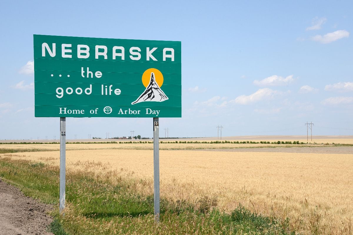 Welcome to Nebraska sign with prairie field on the background.