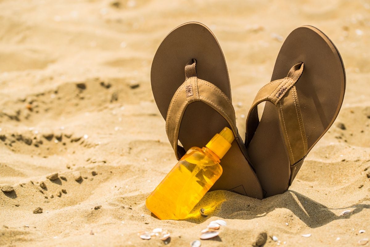 Close up of flip-flops and sunscreen at the beach.