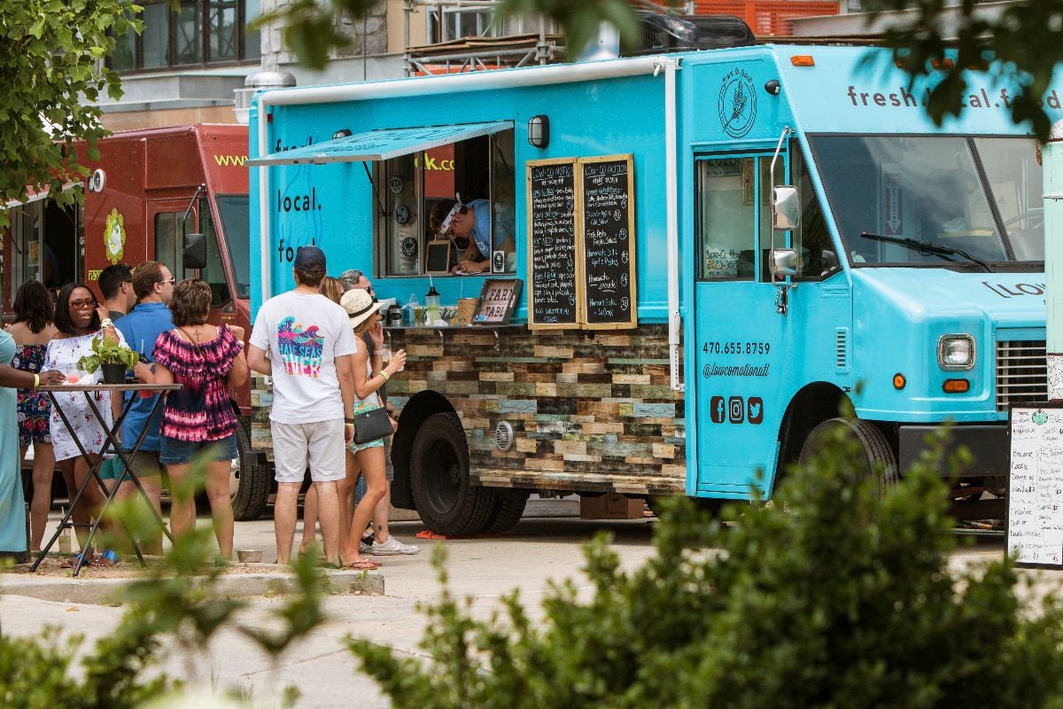 People wait in line and order from a food truck parked at the Old Fourth Ward Food Truck Festival.