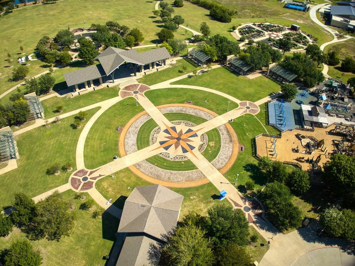 The aerial view of trees and buildings of the Frisco Commons Park.