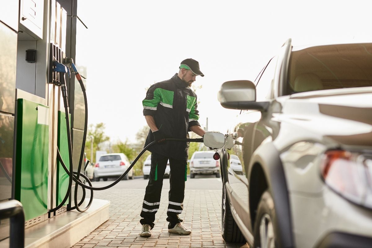 Man in uniform and cap, refilling car.