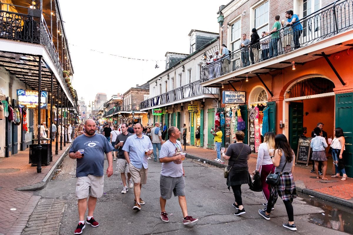People walking and drinking beer on the street.