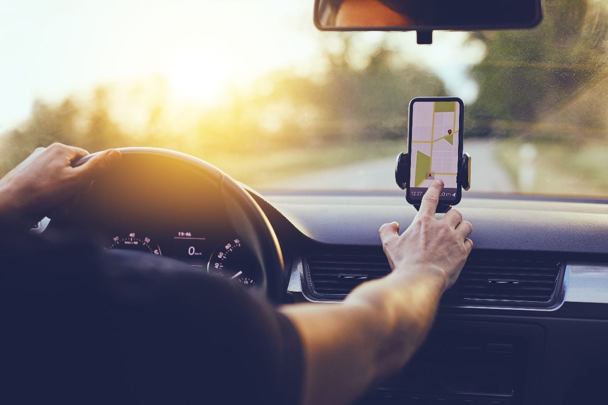 Driver using GPS navigation in mobile phone while driving car.