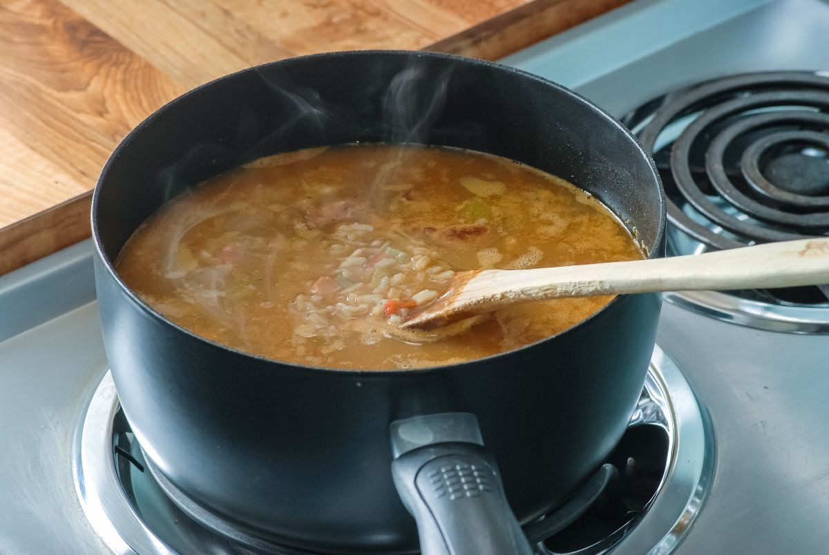 Steam rising from pot of gumbo boiling on electric range.