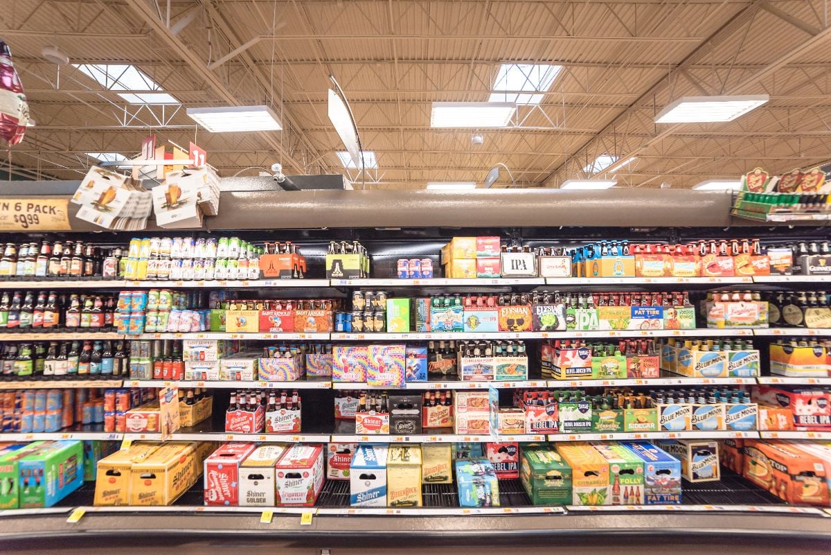 Wide selection of domestic and imported beer at grocery store open fridge.