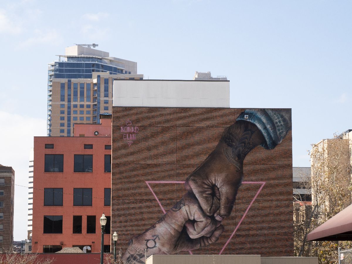 'Inexorable' mural depicting a fist bump with both hands having tattoos.