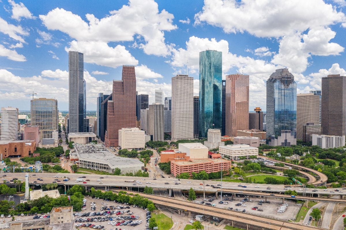 Sky drone view of downtown Houston during day with cityscape and highway in view.
