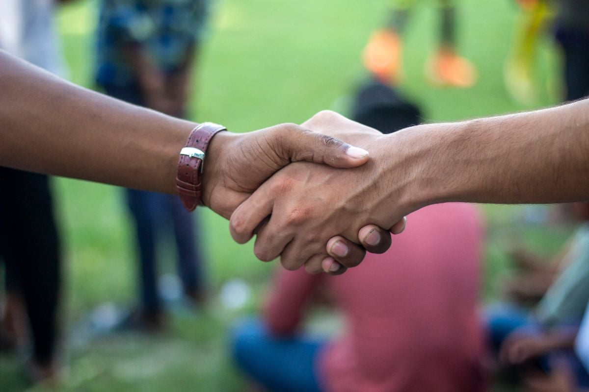 A close up shot captures two hands firmly clasped in a handshake.