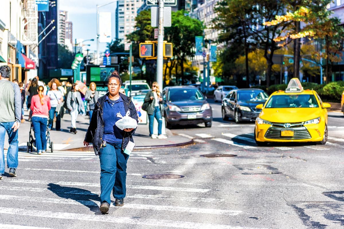 Midtown Manhattan with one african american woman employee worker in blue crossing street.