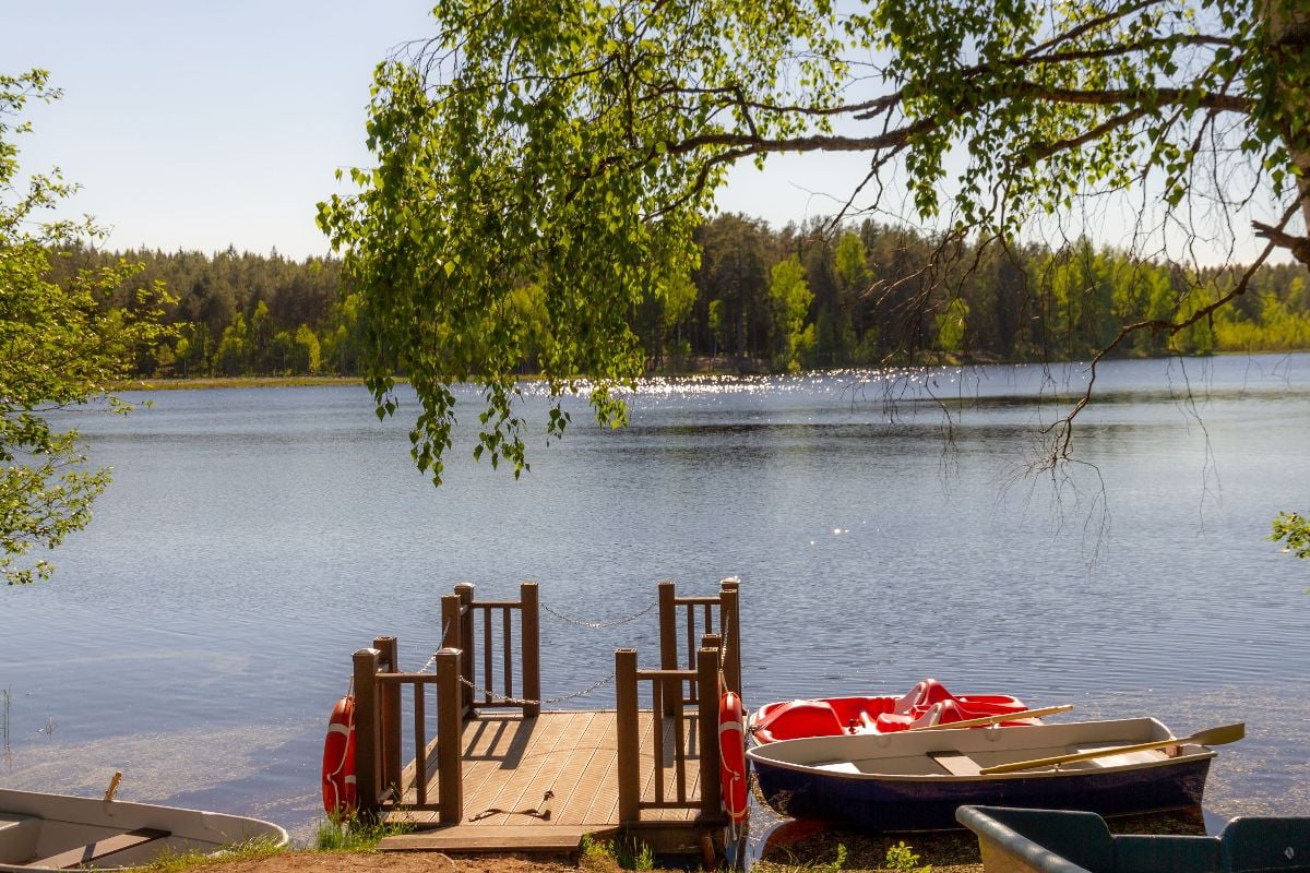 Wooden pier on Pastor Lake shore with rowboats and pedal catamaran.