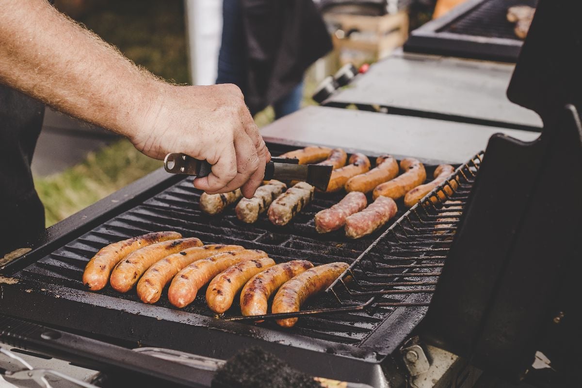 Grilling delicious juicy meat sausages on big grill outdoor.