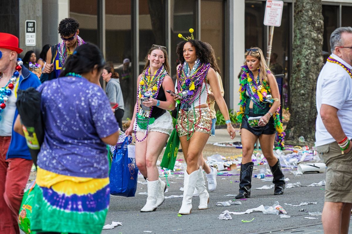 Mardi Gras females with beads around their necks, walking on the street.