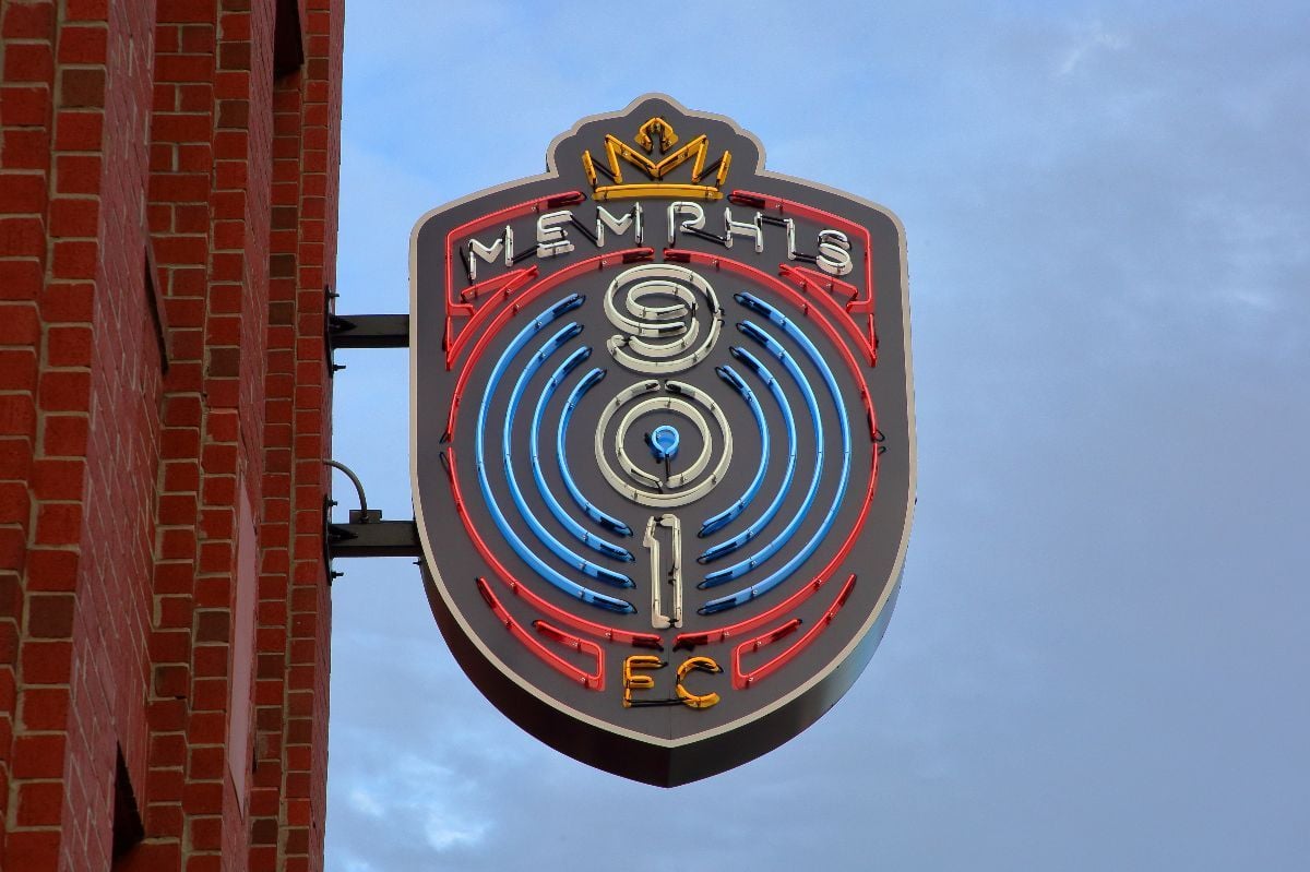 A sign advertising the Memphis 901 FC soccer team illuminated on the outside wall of AutoZone stadium.