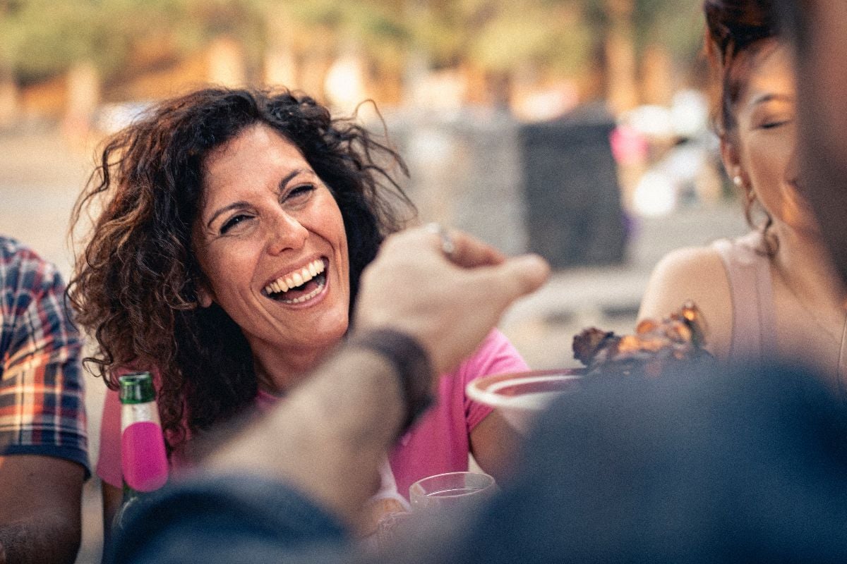 Woman laughing with friends outdoors.
