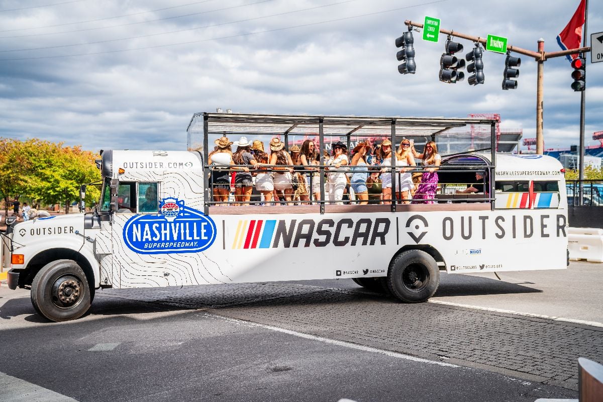 NASCAR-themed open platform bus full of women celebrating and having fun in downtown Nashville.